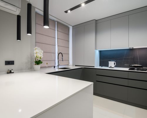 Elegant white and grey luxury kitchen, dining room with kitchen bar and stools in studio apartment interior